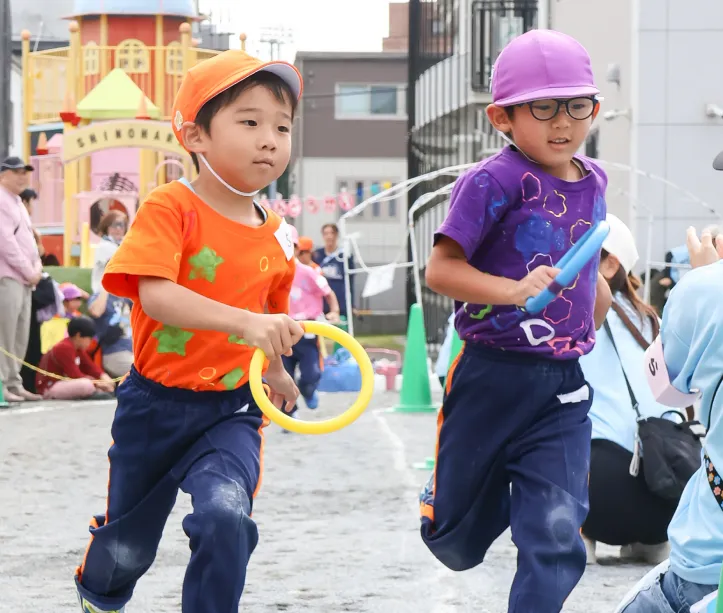 園庭でリングを持って走る園児たちの運動会の様子
