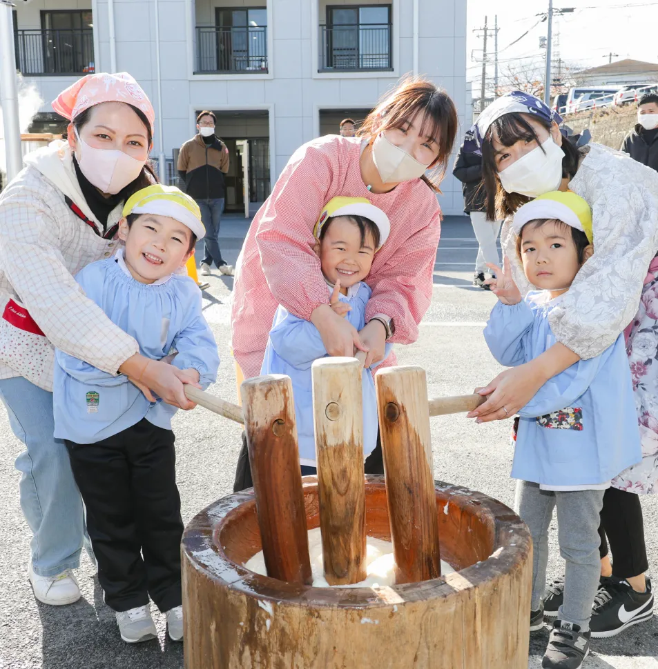 先生や保護者と一緒に餅つきをする園児たち