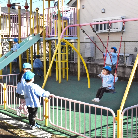 園庭でブランコやすべり台を楽しむ園児たち
