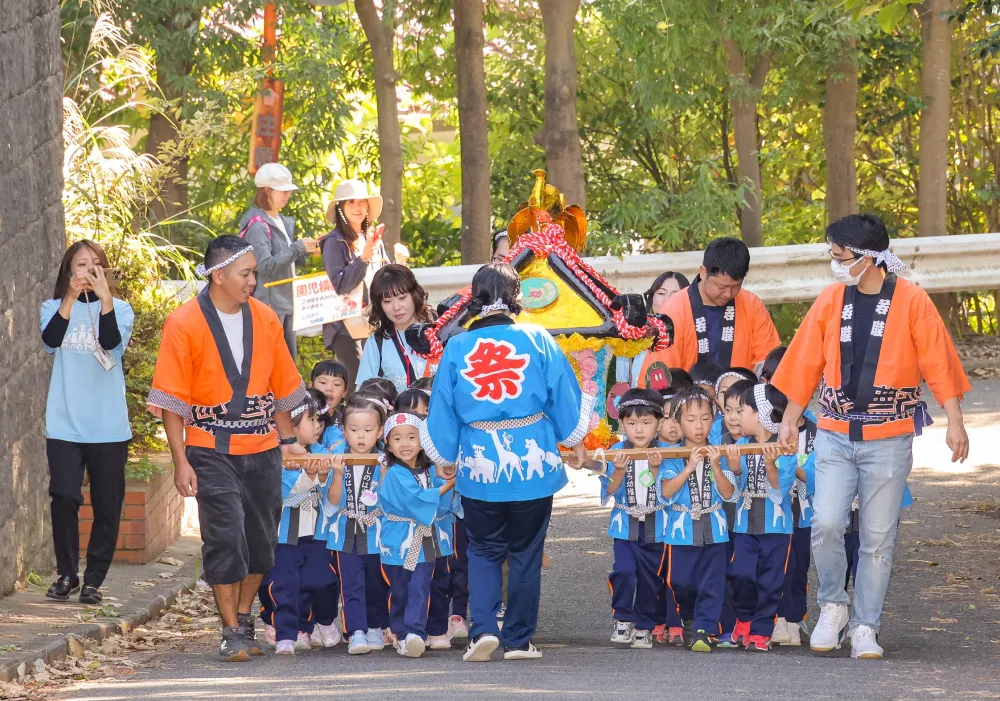 はっぴ姿の園児たちがみこしを担ぐお祭りの様子