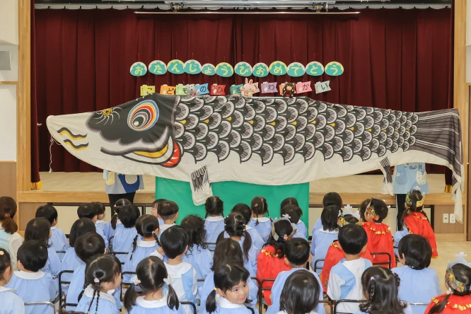 大きなこいのぼりの前で子どもの日を祝う会に参加する子どもたち