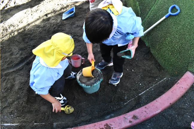 砂場で道具を使って砂遊びをする園児たち