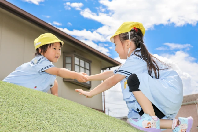 すなおで思いやりのある子を表す、手を差し伸べ合う園児たち