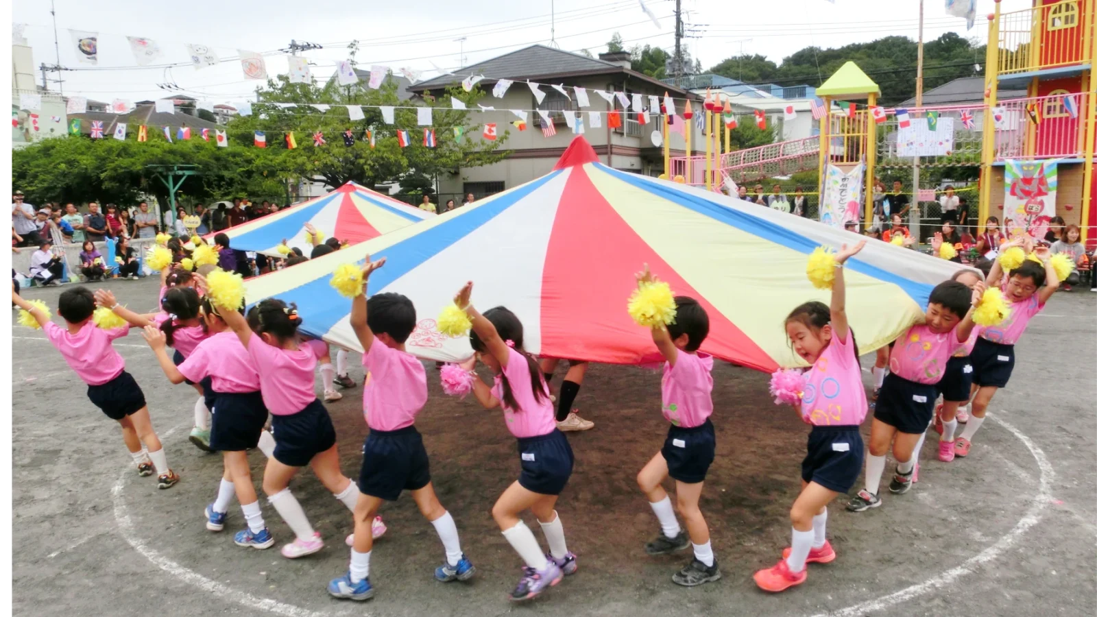 園庭でパラバルーンを楽しむ園児たち