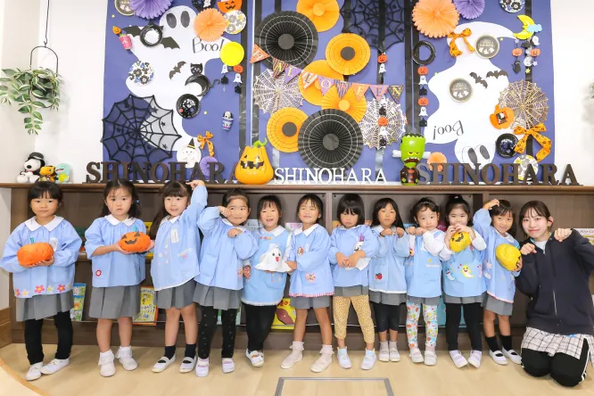 ハロウィンの飾りの前で並ぶ園児たち