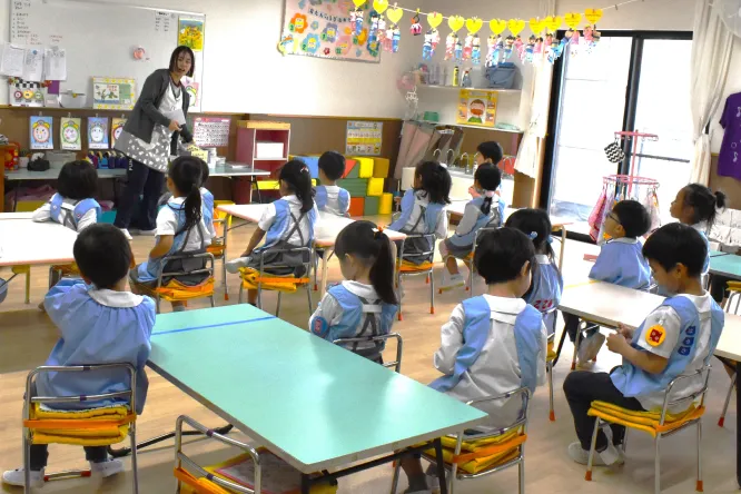 保育室で先生の話を聞く園児たち