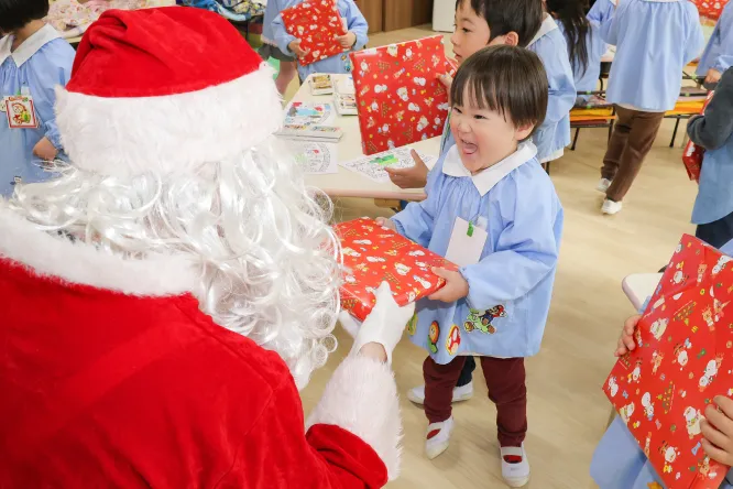 サンタクロースからプレゼントを受け取る園児