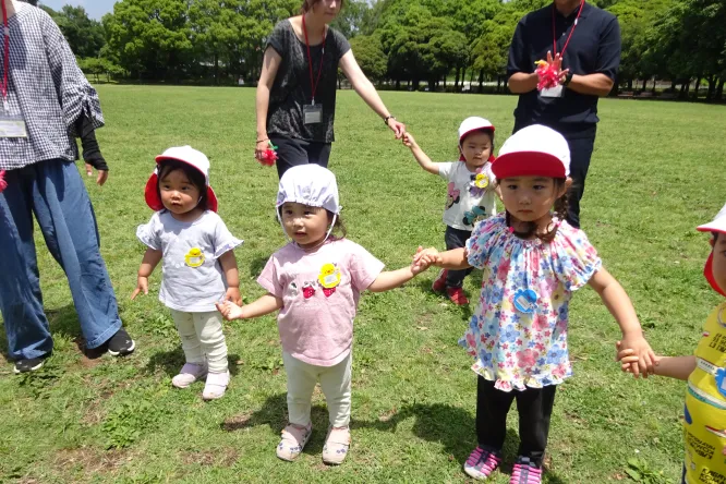 芝生の広場で親子一緒に遊ぶ未就園児たち