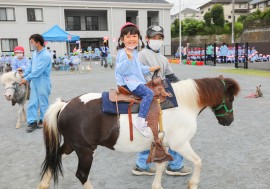 1日動物園で園児が笑顔でポニーに乗る様子